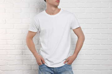 Wall Mural - Man wearing stylish t-shirt near white brick wall, closeup. Mockup for design