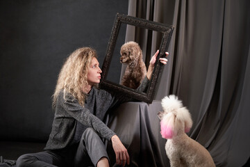 Wall Mural - happy girl with a two dogs in a photo studio on gray. white and chocolate Poodles and curly woman