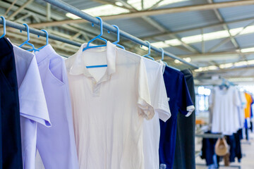 Clothesline indoors without sunlight. Drying clothes using hangers. White shirt on the drying rack. Taking care of clothing.