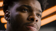© Framestock - Young African American man straight and serious face with confident deep look. Focused worker looks away, blinks eyes, poses on camera. LED lamps on background in studio or office. Close up portrait.