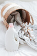 Washing gel liquid laundry detergent and fabric softener, basket with Peshtemal towel on white bed linen with copy space.