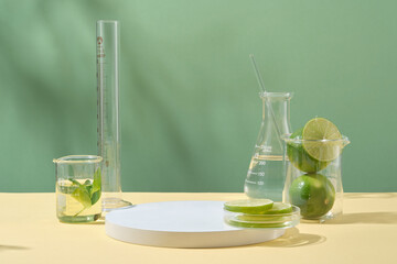 Wall Mural - Front view of fresh limes with lab glassware on green background. Empty space for display cosmetic of lime extract. Concept laboratory and research natural extract making cosmetics