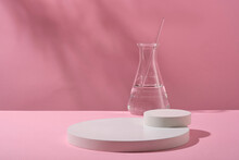 White Round Empty Podiums For Cosmetics Product Presentation And Erlenmeyer Flask Containing Colorless Liquid On Pink Background. Science Laboratory Research And Development Concept