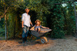 © _KUBE_ - Smiling bearded father in a straw hat is pushing a cart with a happy little daughter. Family weekends together in the backyard. The concept of gardening