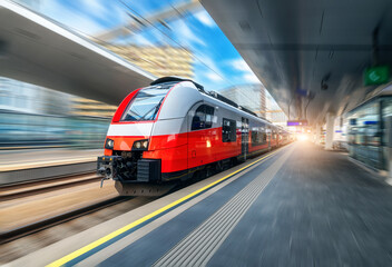 Wall Mural - red high speed train in motion on the railway station at sunset. fast modern intercity train and blu
