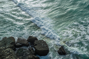 Wall Mural - ocean waves approaching rocky shore. top view.