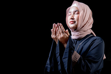 The image of an Asian Muslim woman in the Islamic religion in hijab in cream and black color. She was praying in a beautiful mosque out of respect for God.