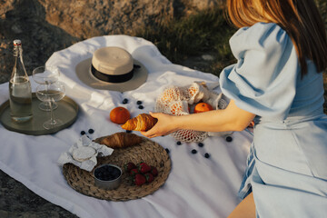 Wall Mural - Summer picnic with wine, eco shopping bag with oranges, straw hat and croissants, berries and cheese brie on the wooden tray.