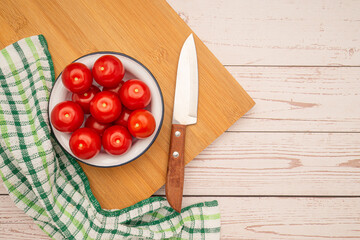 Sticker - Fresh tomatoes on a plate and a knife with a cloth on a wooden cutting board over a table