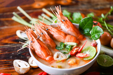 Wall Mural - Thai Food Tom Yum Kung, Hot and sour spicy shrimps prawns soup  curry lemon lime galangal red chili straw mushroom on table food, Shrimp soup on seafood soup bowl with thai herb and spices