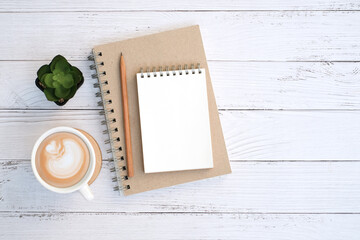 Wall Mural - Flat lay,  Blank notepad and coffee cup with green plant on wooden white table desk background ,Top view with copy space