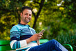 © PRASANNAPIX - Indian man using smartphone at park.