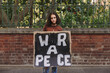 Young peace activist holding an anti-war poster outdoors