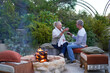 © Caia Image - Happy senior couple drinking wine by fire pit on garden patio
