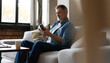 © opolja - Happy smiling senior man using smartphone device while sitting on sofa at home
