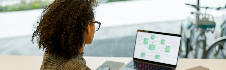 woman freelancer working laptop and making notes while sitting in cozy coworking