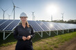 © ADDICTIVE STOCK - Generative AI image of serious female engineer in helmet standing near solar panels windmills and looking at camera during daytime with bright sunshine