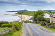 View down the hill to the sandy beach at Low Newton-by-the-Sea in Northumberland, with Dunstanburgh Castle in the distance.