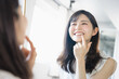 鏡で自分の白い歯の状態をチェック確認して笑顔になる30代の若い女性（ビューティーイメージ）