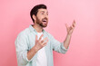 © deagreez - Photo of impressed funky guy dressed teal shirt rising arms looking empty space isolated pink color background