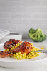 Wall Mural - Oven baked and glazed chicken drumsticks with curry, broccoli brown rice on a plate