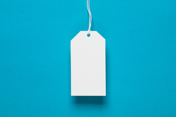 White blank price tag on string, blue background