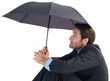 Businessman holding umbrella sitting on the floor