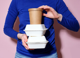 Woman dressed in bright blue shirt holding a pile of takeaway food boxes