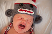 Five Week Old Baby In A Sock Monkey Hat Cries For Attention; Lincoln, Nebraska, United States Of America