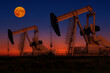 © Designpics - Glowing colourful pumpjacks at sunrise with glowing sky and full moon in the background, West of Airdrie; Alberta, Canada