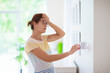 © famveldman - Woman adjusting thermostat. Central heating.