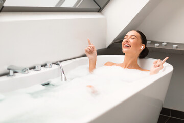 Wall Mural - Woman Taking Bath Enjoying Relaxing Playlist Wearing Earbuds In Bathroom