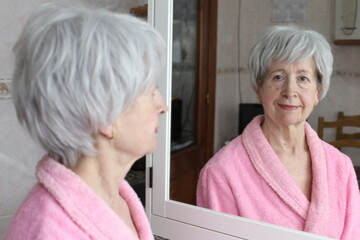 Cute senior woman looking at her reflection in the bathroom