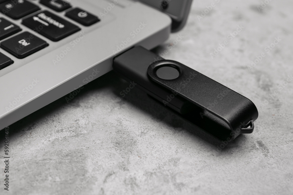 Laptop with USB flash drive on grunge background, closeup