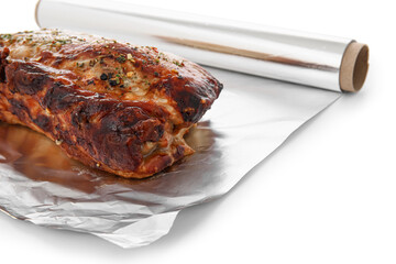 Aluminium foil roll with piece of tasty baked meat on white background, closeup