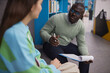 © Seventyfour - Portrait of black man as mental health specialist talking to teenage girl in therapy session at college library
