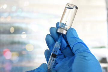 Medical personnel filling a syringe needle with generic vaccine booster from vial