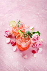 Classic pink daiquiri with rum, orange liqueur and lime juice served as a Valentine's Day gift in two glasses and decorated with roses and hearts