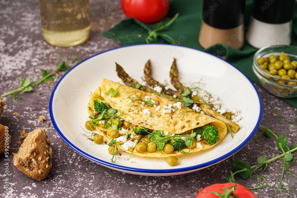 Tasty omelet with broccoli, asparagus and pea on grey background