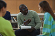 © Seventyfour - Portrait of black adult man as mental health therapist talking to teenage girl in support group session