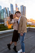 Happy young beautiful couple on a rooftop just after engagement, marriage proposal showing a ring with a rock on girl hand. Romantic date on Saint Valentine's Day. Urban cityscape on background