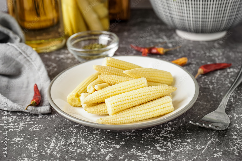 Plate with canned baby corn cobs on grey grunge background
