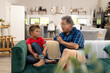 © WavebreakMediaMicro - Caucasian senior man gesturing and talking with cute grandson while sitting on sofa in living room