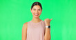 © Nina L/peopleimages.com - Woman face, pointing gesture and green screen with happiness and smile showing advertisement. Portrait, isolated and studio background with a happy young female point to show mock up announcement