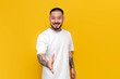 © Богдан Маліцький - unshaven asian man in white t-shirt says hello and makes handshake gesture on yellow isolated background