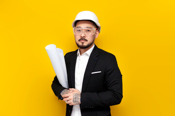 Wall Mural - asian foreman in black suit with papers and projects on yellow isolated background, korean civil engineer in hardhat