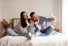 Happy Asian Family With Smartphone Chatting At Home Via Video Link Online And Greeting