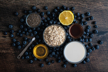 Wall Mural - Blueberry Chia Oatmeal Ingredients on a Wood Table: Old-fashioned oats, fresh blueberries, honey, and other ingredients