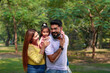 © Niks Ads - Happy Young indian parents with their cute little daughter sitting at park or garden.