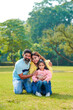 © Niks Ads - Happy Young indian parents with their cute little daughter sitting at park or garden.